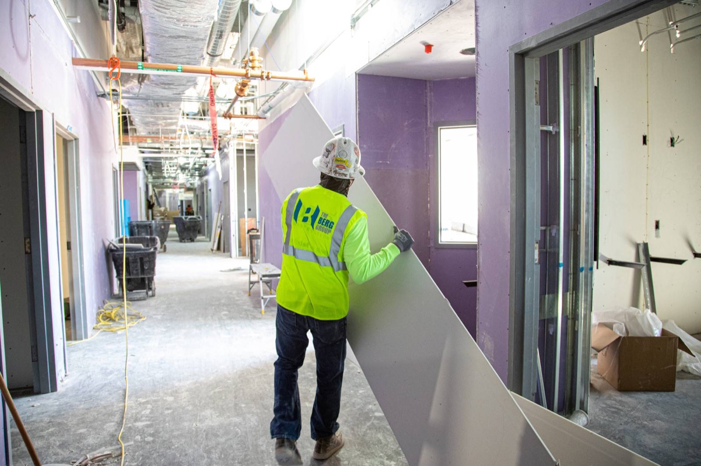 Berg Group tradesman carrying drywall down a corridor